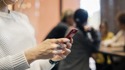 Kvinna med mobiltelefon, kollegor i bakgrunden, tema p&aring;verkansf&ouml;rs&ouml;k.