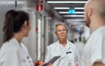 &Auml;ldre v&aring;rdpersonal pratar med kollegor i sjukhuskorridor.