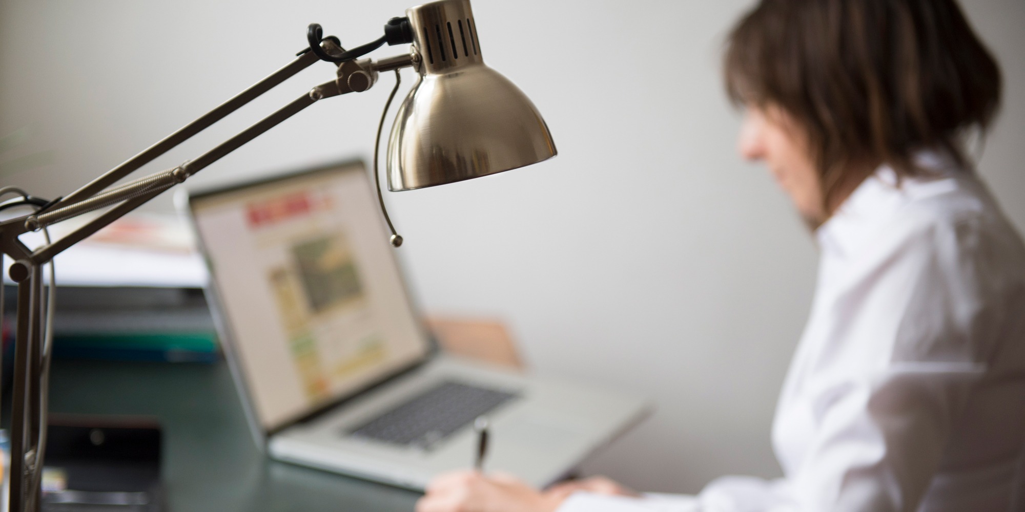 Kvinna vid dator med lampa i f&ouml;rgrunden