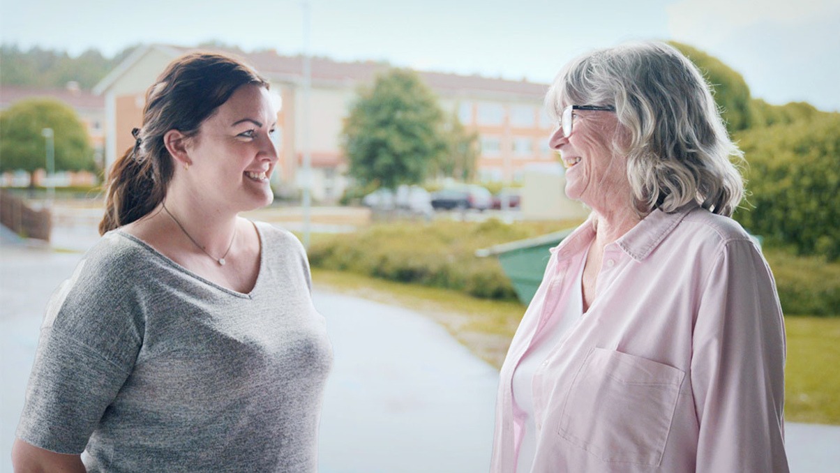 Tv&aring; kvinnor st&aring;r utomhus och tittar p&aring; varandra