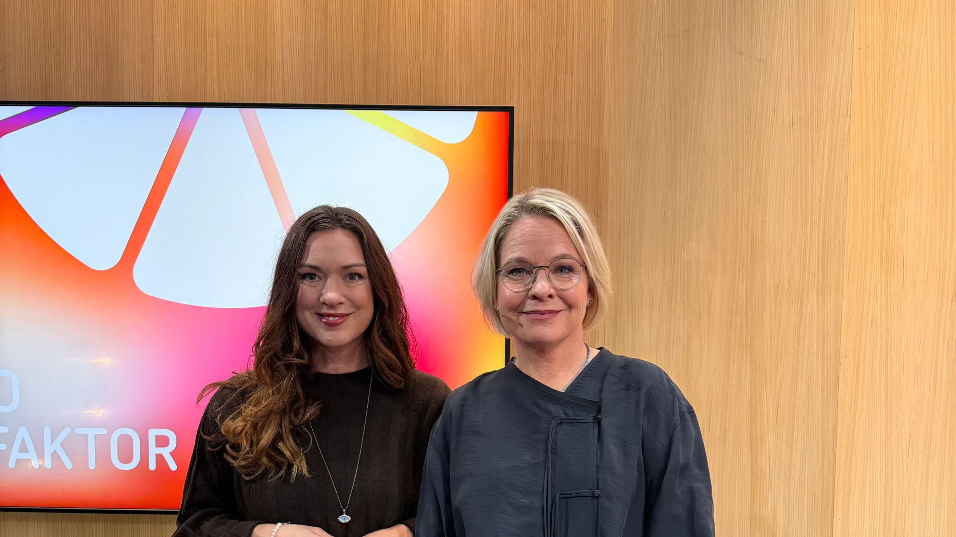 Tv&aring; kvinnor st&aring;r bredvid varandra framf&ouml;r en TV