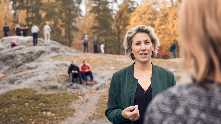 En kvinna som st&aring;r framf&ouml;r en grupp m&auml;nniskor.