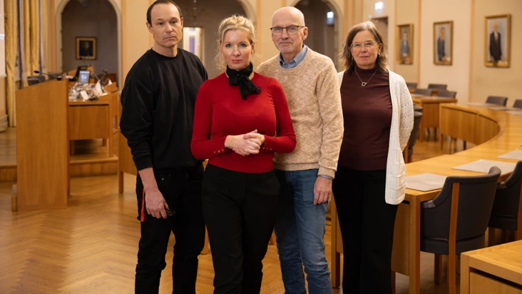Fyra personer ur Eskilstuna kommuns ledning och politiska n&auml;mnder st&aring;r i ett stort m&ouml;tesrum.
