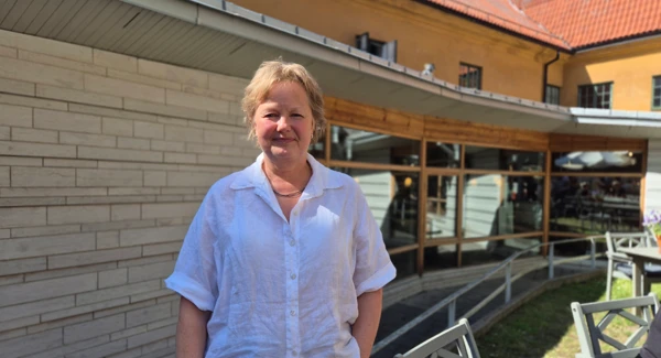 En kvinna st&aring;r utomhus framf&ouml;r ett hus.