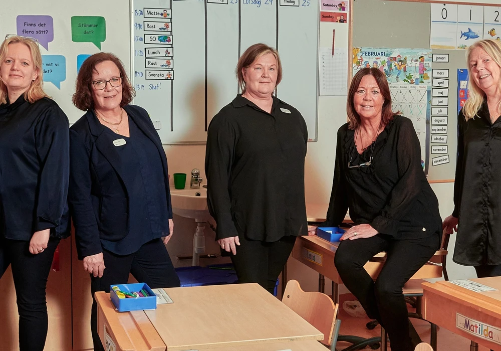 Skolan med Stockholms n&ouml;jdaste medarbetare. En personalgrupp poserar i ett klassrum.
