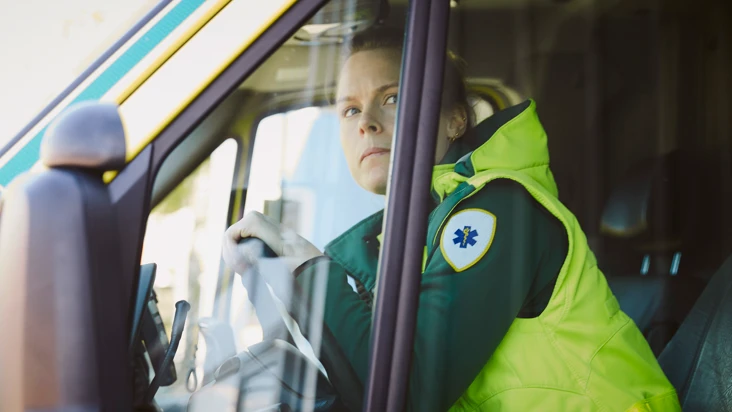 En kvinna som sitter i f&ouml;rars&auml;tet p&aring; en ambulans.