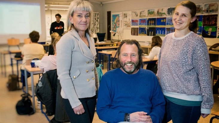 Tre personer st&aring;r i ett klassrum.