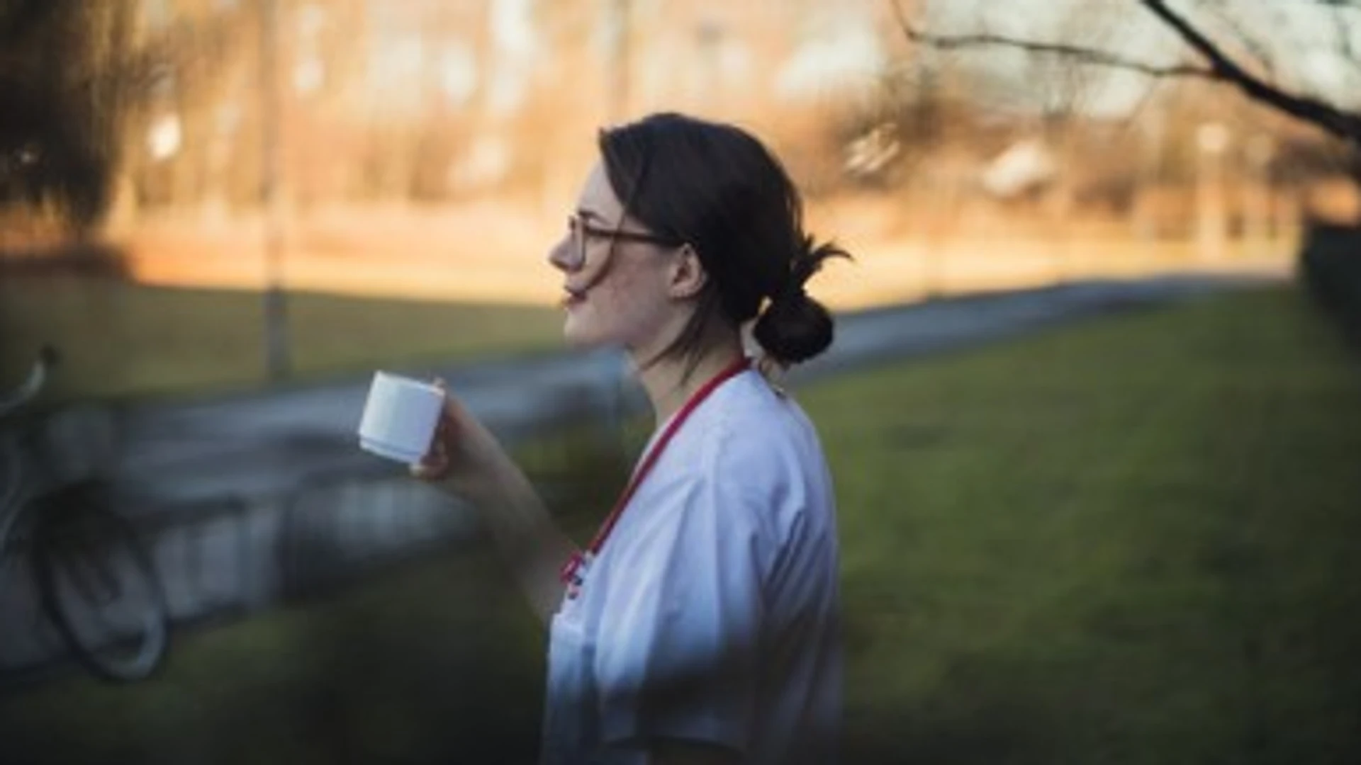 En kvinna med en kopp kaffe i en park.