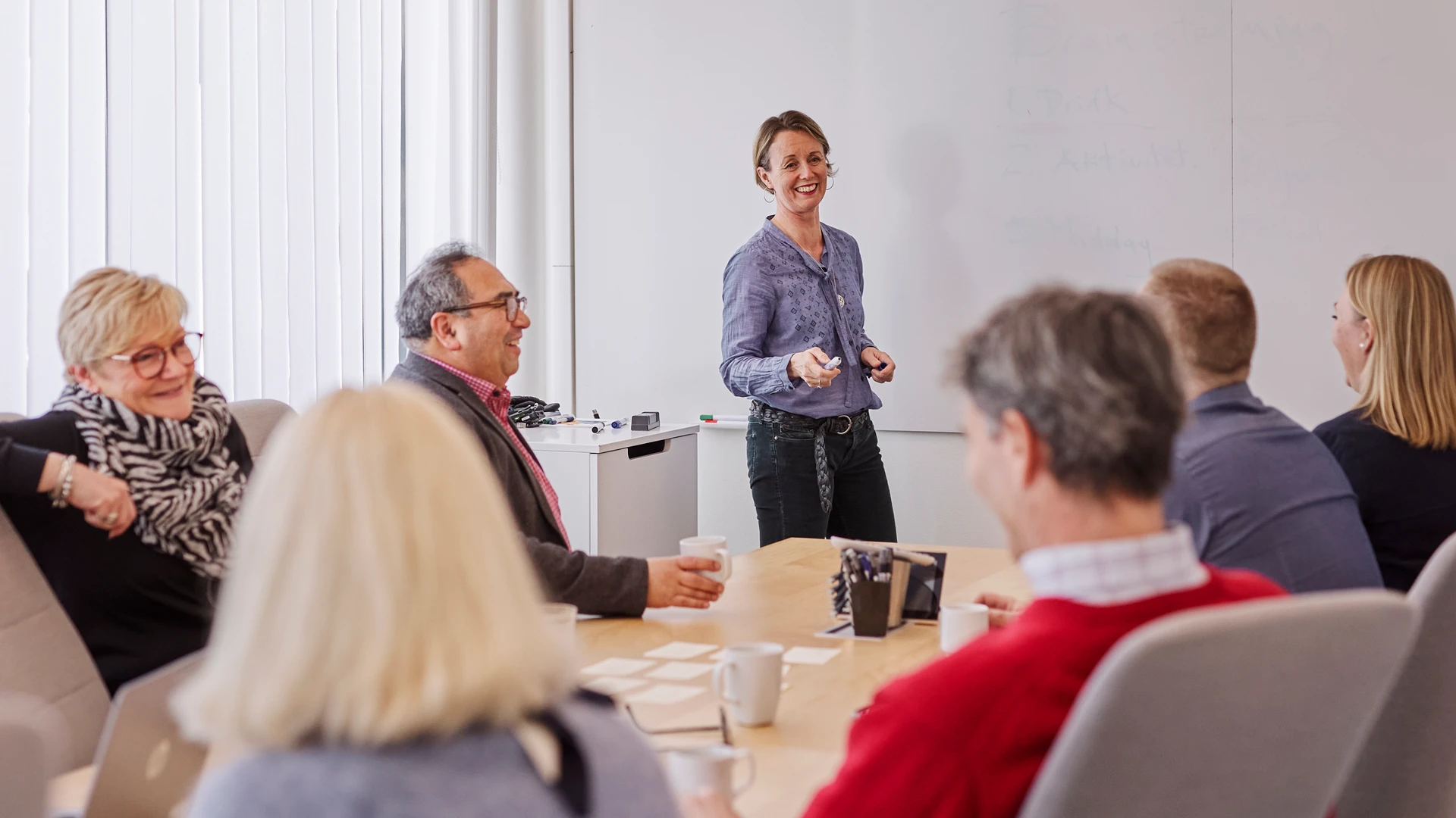 En kvinna som h&aring;ller en presentation f&ouml;r en grupp m&auml;nniskor.