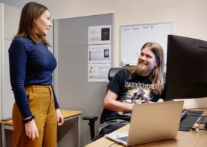 Två medarbetare i Robertsfors pratar med varandra vid dator. 
