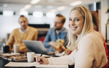 En grupp m&auml;nniskor som sitter runt ett bord med en b&auml;rbar dator.
